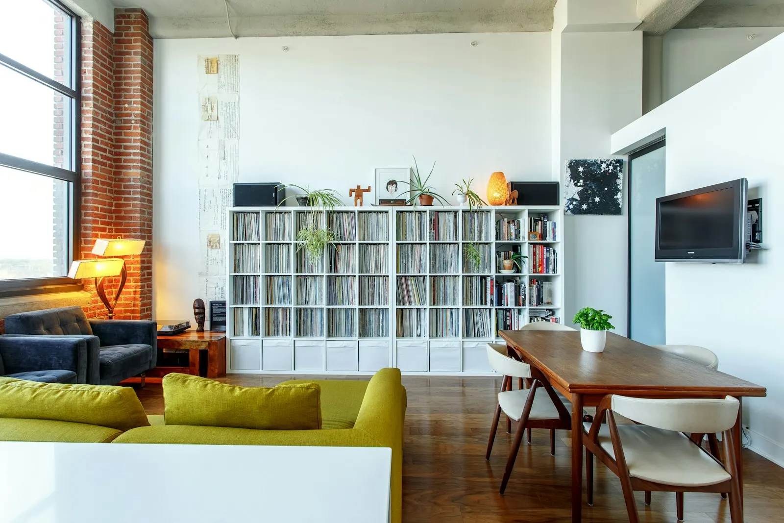 Open living and dining with a full-height media wall, cove lighting and a stone dining table