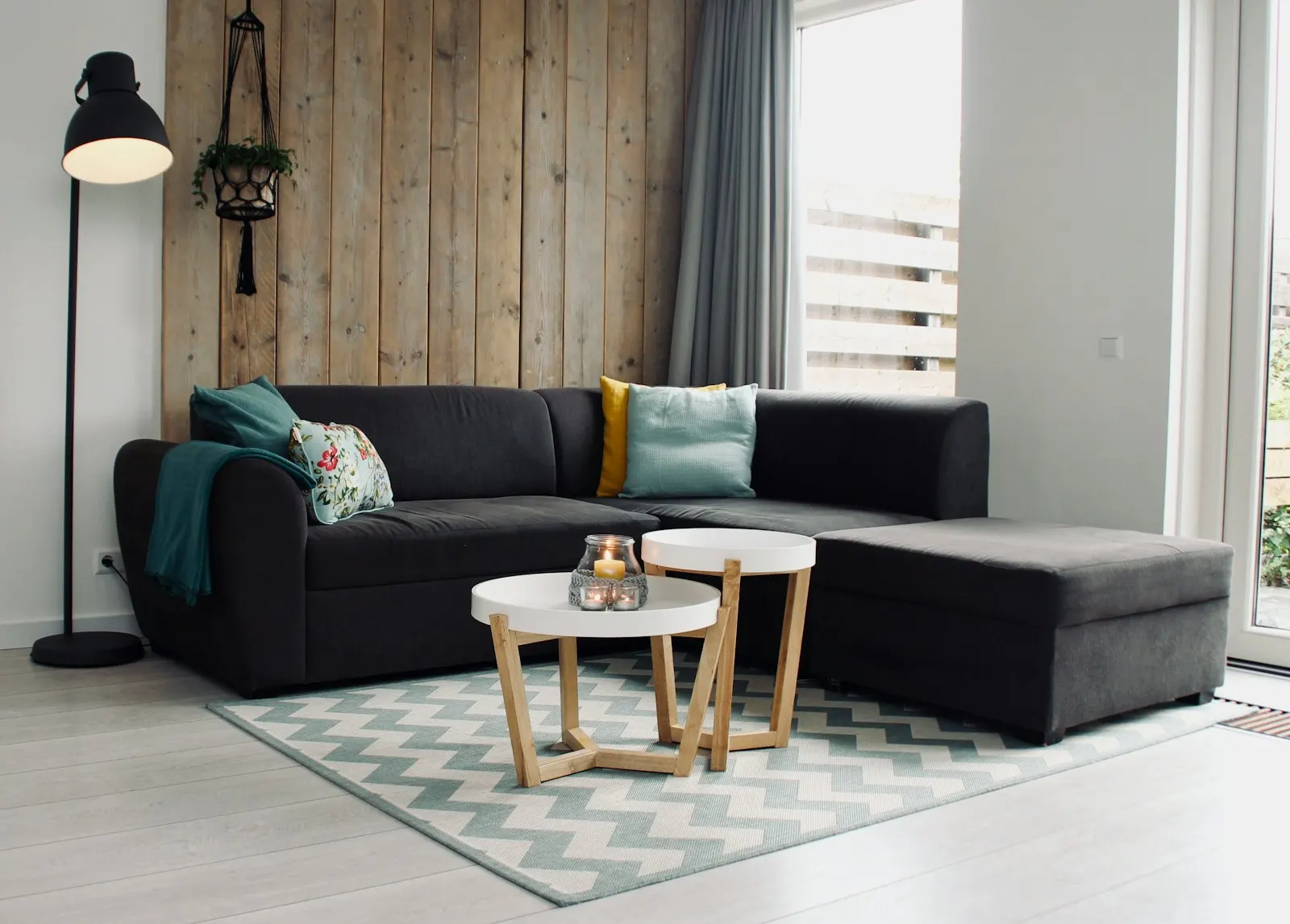 Wood-panelled media wall with an L-shaped sofa, floor lamp and marble-top coffee table